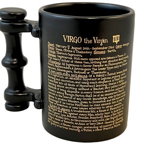 K&ouml;nnte beinhalten: Schwarze Keramiktasse mit goldenem Henkel und Inschrift. Die Inschrift lautet "VIRGO the Virgin" und enth&auml;lt Informationen &uuml;ber das Sternzeichen, einschlie&szlig;lich seines Planeten, seiner Daten, seiner Farben und seiner Elemente.