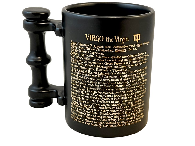 K&ouml;nnte beinhalten: Schwarze Keramiktasse mit goldenem Henkel und Inschrift. Die Inschrift lautet "VIRGO the Virgin" und enth&auml;lt Informationen &uuml;ber das Sternzeichen, einschlie&szlig;lich seines Planeten, seiner Daten, seiner Farben und seiner Elemente.