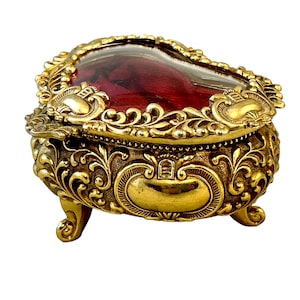 Vintage Schmuckschatulle in Herzform, goldfarbenes geprägtes Metall, Glasdeckel, rotes Samtfutter, aufwendiges Eitelkeitsdekor