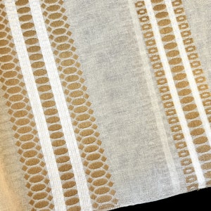 May include: A close-up of a sheer fabric with a repeating pattern of brown and white stripes. The fabric has a subtle sheen and a delicate texture.