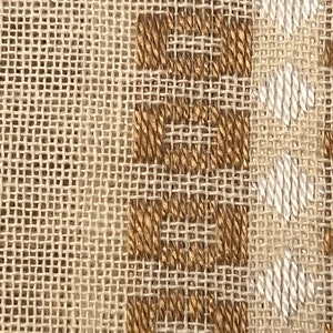 May include: Close-up of a woven fabric with a brown and white pattern. The fabric has a rough texture and a natural look.