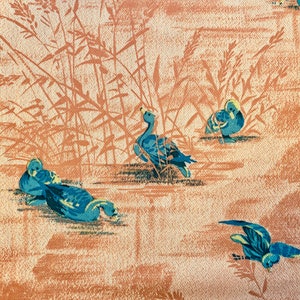 May include: A vintage wallpaper design featuring blue ducks swimming in a pond with brown reeds in the background.