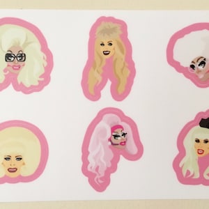 May include: Six pink and white stickers featuring cartoon illustrations of women with large hair and makeup. The stickers are on a white background.