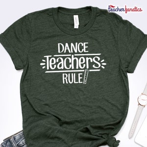 May include: A dark green t-shirt with the text "DANCE TEACHERS RULE" in white lettering. A ruler is next to the word "RULE".