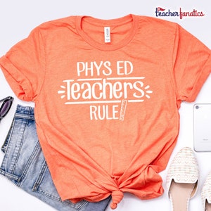 May include: Orange t-shirt with the text "PHYS ED Teachers RULE" in white lettering with a ruler graphic.