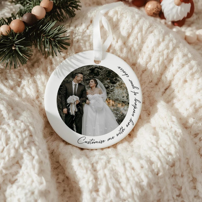 Puede incluir: Adorno de cer&aacute;mica blanca con una foto de una pareja de novios. El adorno tiene una cinta blanca para colgar y el texto "Personal&iacute;zame con cualquier texto de tu elecci&oacute;n".