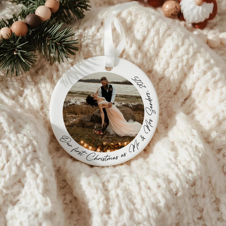 Puede incluir: Un adorno navide&ntilde;o de cer&aacute;mica blanca con una foto de una pareja bailando. El adorno tiene el texto "Our first Christmas as Mr & Mrs Sanders. 2025" en una fuente de escritura. Se adjunta una cinta blanca para colgar.