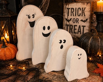 May include: A set of four white wooden ghost figures of varying heights, each featuring a unique black painted facial expression. The ghosts have rounded tops and smooth, curved edges, standing upright as decorative items for the Halloween season.