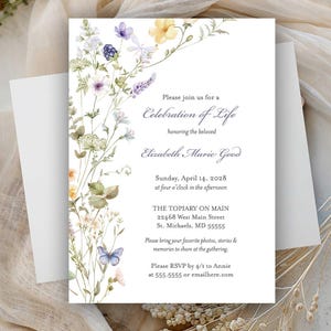 May include: A white invitation card with floral watercolor illustrations. The text reads "Celebration of Life" and includes details for the event. The card is accompanied by a white envelope.