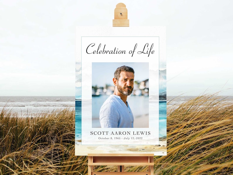 May include: A white poster with a blue watercolour background and a photo of a man. The poster says "Celebration of Life" and "Scott Aaron Lewis, October 8, 1965 - July 12, 2022".