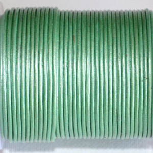 Può includere: Un rotolo di cordoncino in pelle verde chiaro. Il cordoncino è liscio e lucido, ed è avvolto strettamente attorno al rotolo.