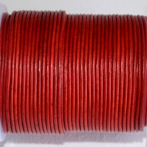 May include: A spool of red leather cord. The cord is wound tightly around the spool, creating a smooth, even surface.