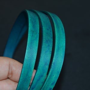 May include: Three strands of teal blue leather cord, rolled into a circle, showing the texture of the leather.