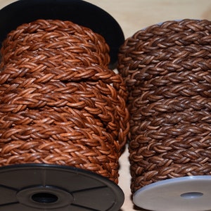 Op de afbeelding: Twee spoelen met gevlochten lederen koord. De ene spoel is bruin en de andere is lichtbruin.