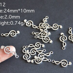 May include: A close-up of silver metal music note charms. The charms are 2.4 cm by 1 cm and have a 2 mm hole. The charms are scattered on a dark gray surface. CN12 Size: 24mm*10mm Hole: 2.0mm Weight: 0.74g/