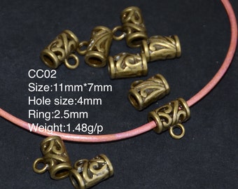 May include: A set of eight gold-toned metal end caps with an ornate design. The end caps are approximately 11 mm in length and 7 mm in width. Each end cap has a 4 mm hole and a 2.5 mm ring. The text "CC02" is visible in the image. The end caps are displayed on a pink cord.