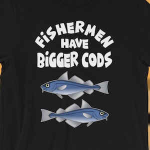 May include: Black t-shirt with white text that reads "Fishermen Have Bigger Cods". Two cartoon cod fish are below the text.