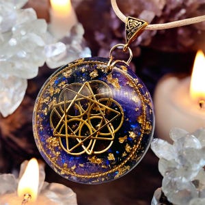 Könnte beinhalten: Ein runder Anhänger mit einer tiefvioletten und blauen Harzbasis, die mit Blattgoldflocken durchsetzt ist. Ein geometrisches Sternsymbol aus goldfarbenem Metall ist mittig auf der Oberfläche platziert. Der Anhänger hängt an einer hellen Kordel.