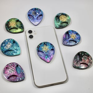 Puede incluir: Siete agarres para teléfono de resina con forma de extraterrestre con diferentes patrones de galaxia y diseños geométricos dorados.