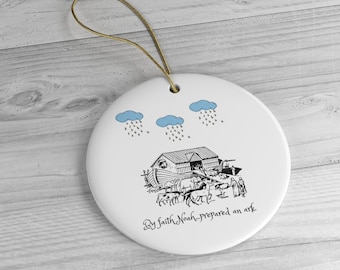 May include: A white ceramic ornament with a black and white illustration of Noah's Ark with animals and people boarding the ark. Three blue clouds with rain are above the ark. The text "By faith Noah prepared an ark" is written below the ark.