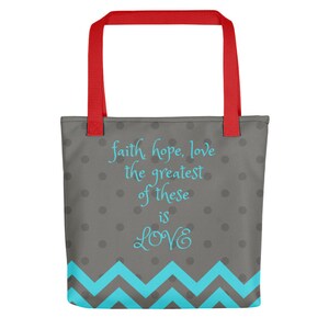 K&ouml;nnte beinhalten: Eine graue Tragetasche mit roten Henkeln und einem blauen Zickzackmuster am Boden. Die Tasche hat wei&szlig;e Punkte und den Text "faith hope, love the greatest of these is LOVE" in blau.