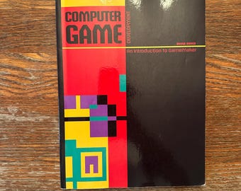 May include: A book titled "COMPUTER GAME DEVELOPMENT" with a colorful design. The cover features the title in large, bold letters, with a red, yellow, and black geometric design on the left side. The subtitle reads "An Introduction to GameMaker".
