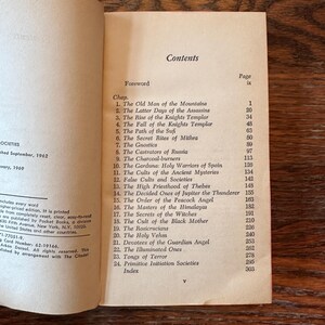 May include: An open book showing the contents page. Chapter titles include "The Latter Days of the Assassins" and "The Secrets of the Witches." The book was published in 1962 by Pocket Books.