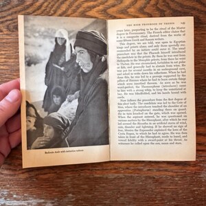 May include: A white ceramic mug with a black handle and the text "But First, Coffee" in a bold, black font. The mug is set against a blurred background, suggesting a cosy setting.