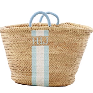 Könnte beinhalten: Ein großer, naturgeflochtener Korb mit blauen Henkeln und einem blauen und weißen Streifen auf der Vorderseite. Der Korb ist mit den Initialen "HIJ" personalisiert.