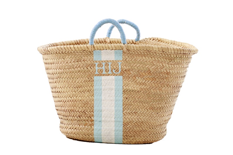 May include: A large, natural woven basket with blue handles and a blue and white stripe down the front. The basket is personalized with the initials "HIJ".