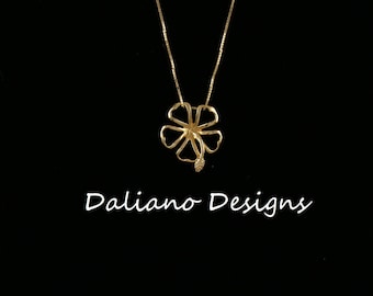 May include: A gold necklace with a delicate flower pendant. The pendant is made of a single piece of metal and has a detailed design.