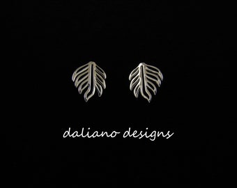 May include: A pair of silver earrings with a leaf design. The earrings are small and delicate.