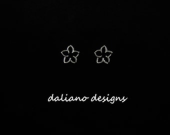 May include: A pair of silver earrings with a delicate flower design. The earrings are small and simple, making them a great choice for everyday wear.