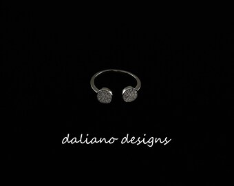 May include: A silver ring with two round, pave-set stones.