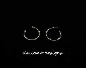 May include: A pair of silver hoop earrings with a bamboo-inspired design. The earrings are simple and elegant, and would make a great gift for any occasion.