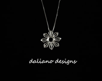 May include: A silver necklace with a geometric flower pendant. The pendant is a stylized sun with a circular hole in the center.