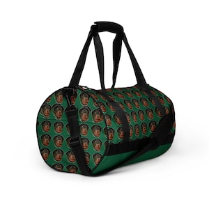 Könnte beinhalten: Grüne Reisetasche mit schwarzem Riemen und einem sich wiederholenden Muster von Rottweiler-Hundegesichtern.