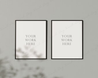 Peut inclure: Deux impressions d'art encadrées en noir avec des fonds blancs sont accrochées à un mur gris. Le texte "YOUR WORK HERE" est imprimé en noir sur chaque impression. Une ombre de feuilles est projetée sur le mur et les impressions.