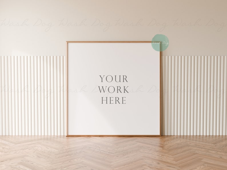 May include: A white frame with a wooden border sits on a light wood floor. The frame is against a white wall with vertical grooves. The text "YOUR WORK HERE" is printed in black on the white background inside the frame.