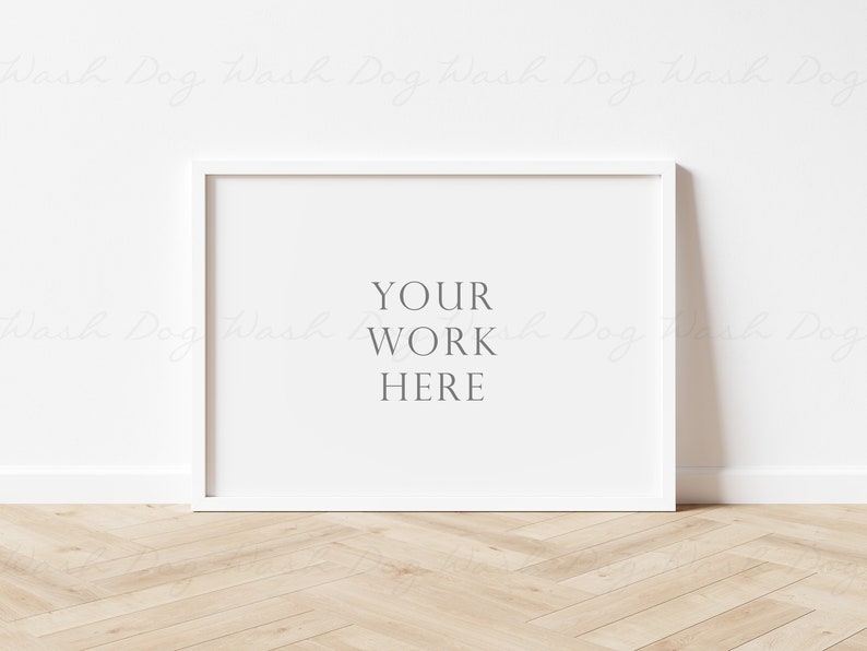 May include: White picture frame mockup on a white wall with a wood floor. The frame is empty with the text "YOUR WORK HERE" in the center.