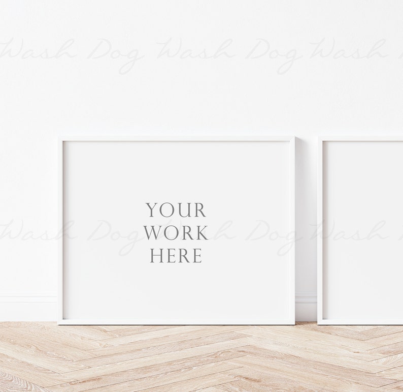 May include: Two white picture frames on a light wood floor. The frame on the left has the text "YOUR WORK HERE" inside.