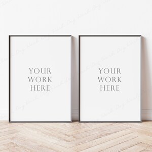 May include: Two black framed posters with white backgrounds and the text "YOUR WORK HERE" in the center of each poster.
