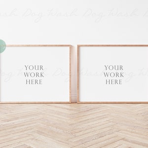 May include: Two wooden framed picture frames with white mats and the text "YOUR WORK HERE" in each frame. The frames are on a light wood floor.