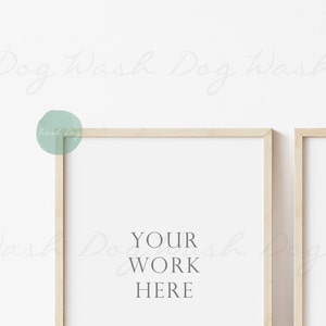 May include: Two light wood picture frames with white mats, hanging on a white wall. The left frame has the text "YOUR WORK HERE" inside.