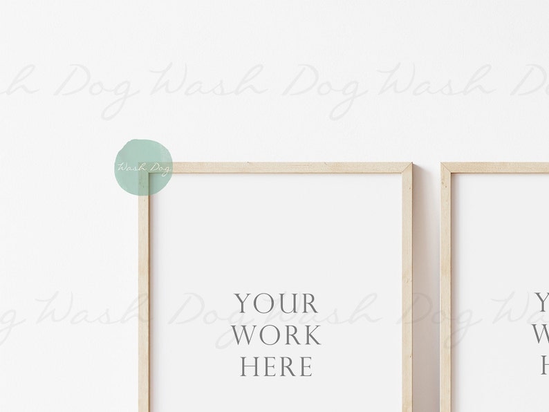 May include: Two light wood picture frames with white mats, hanging on a white wall. The left frame has the text "YOUR WORK HERE" inside.