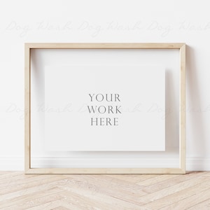 Peut inclure: Un cadre en bois clair avec un passe-partout blanc et le texte "YOUR WORK HERE" au centre. Le cadre est posé sur un sol en bois clair.