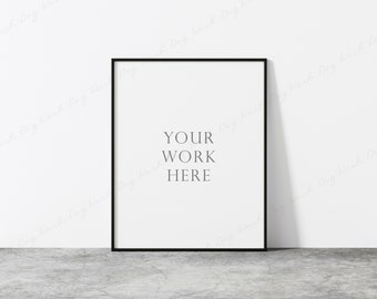 Könnte beinhalten: Ein schwarzer Bilderrahmen mit einem weißen Passepartout und dem Text "YOUR WORK HERE" an einer weißen Wand.