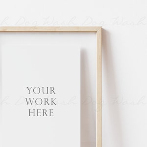 May include: A light wood frame with a white mat and the text "YOUR WORK HERE" in the center. The frame is hanging on a white wall.