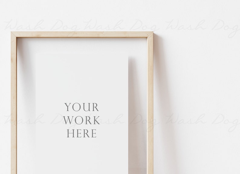 May include: A light wood frame with a white mat and the text "YOUR WORK HERE" in the center. The frame is hanging on a white wall.