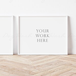 May include: Two white picture frames on a light wood floor. The frame on the right has the text "YOUR WORK HERE" in the center.